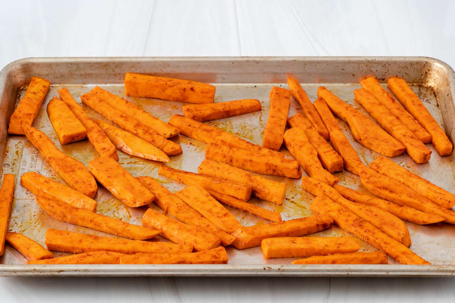 Sweet potato wedges seasoned on a baking sheet.