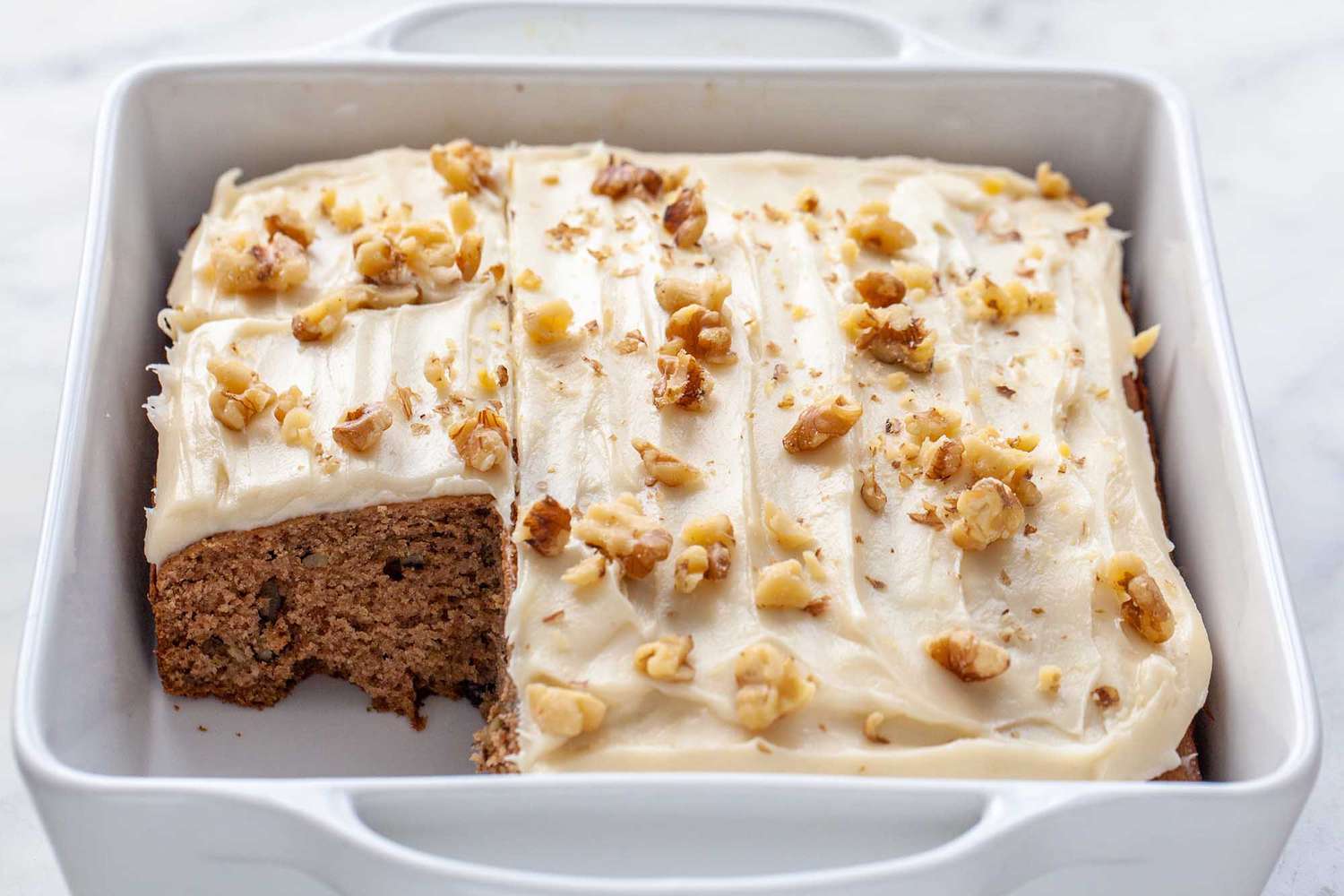 spiced applesauce cake with white frosting and nuts