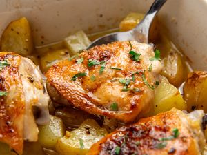Garlic butter chicken with potatoes garnished with herbs in a tray