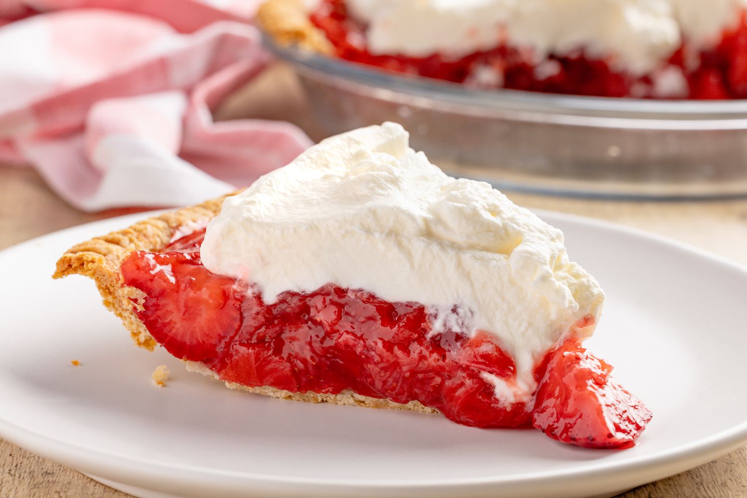 slice of fresh strawberry pie on a plate (and in the background, the rest in a pie dish)