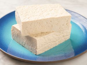 Two rectangular slices of tofu stacked on a blue ceramic plate