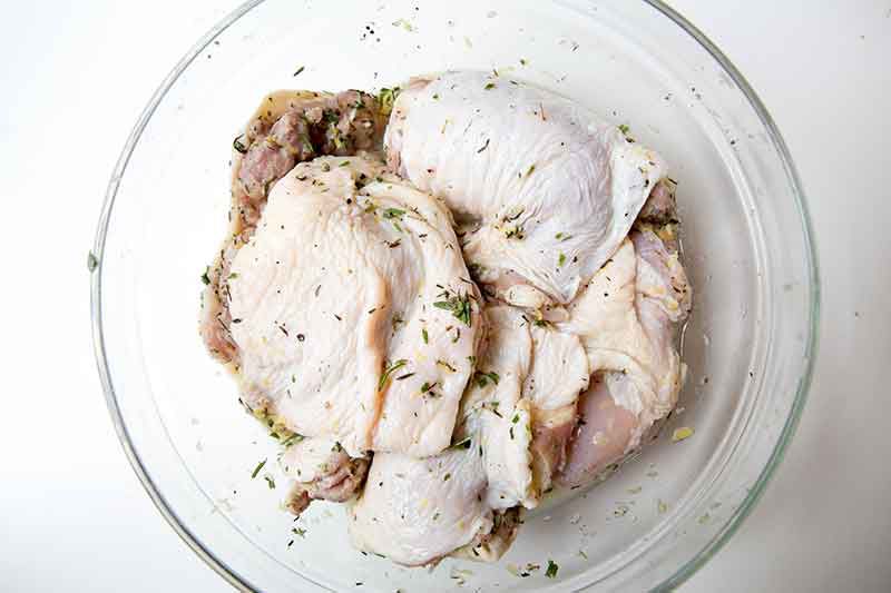 Raw chicken in a bowl marinated and zested with lemon