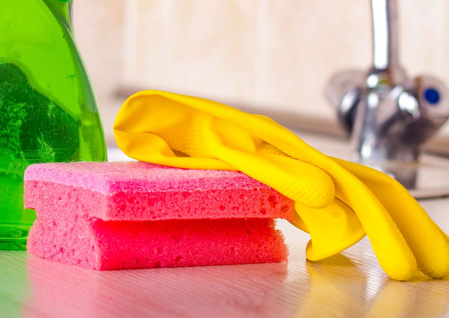 A sponge and a yellow dish glove next to a sink