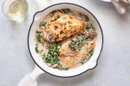 Creamy chicken Florentine in skillet, and next to it, a glass of wine 