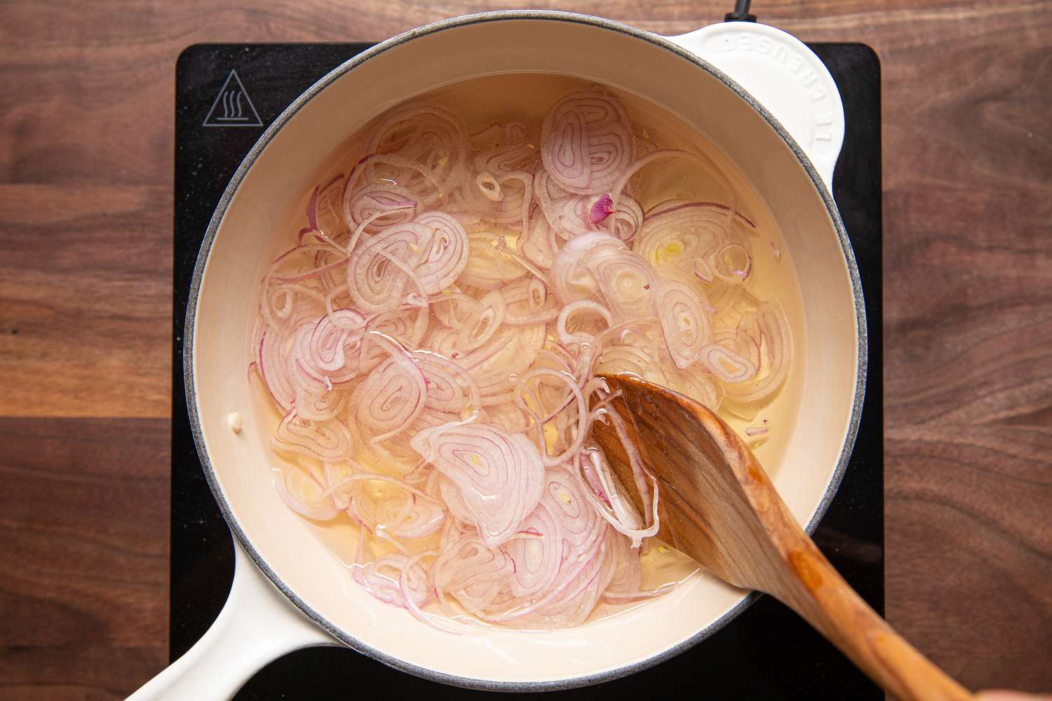 In a Pot on an Portable Stove, Sliced Shallots Cooking in Oil and Mixed Using a Wooden Spoon for Homemade Chili Crisp