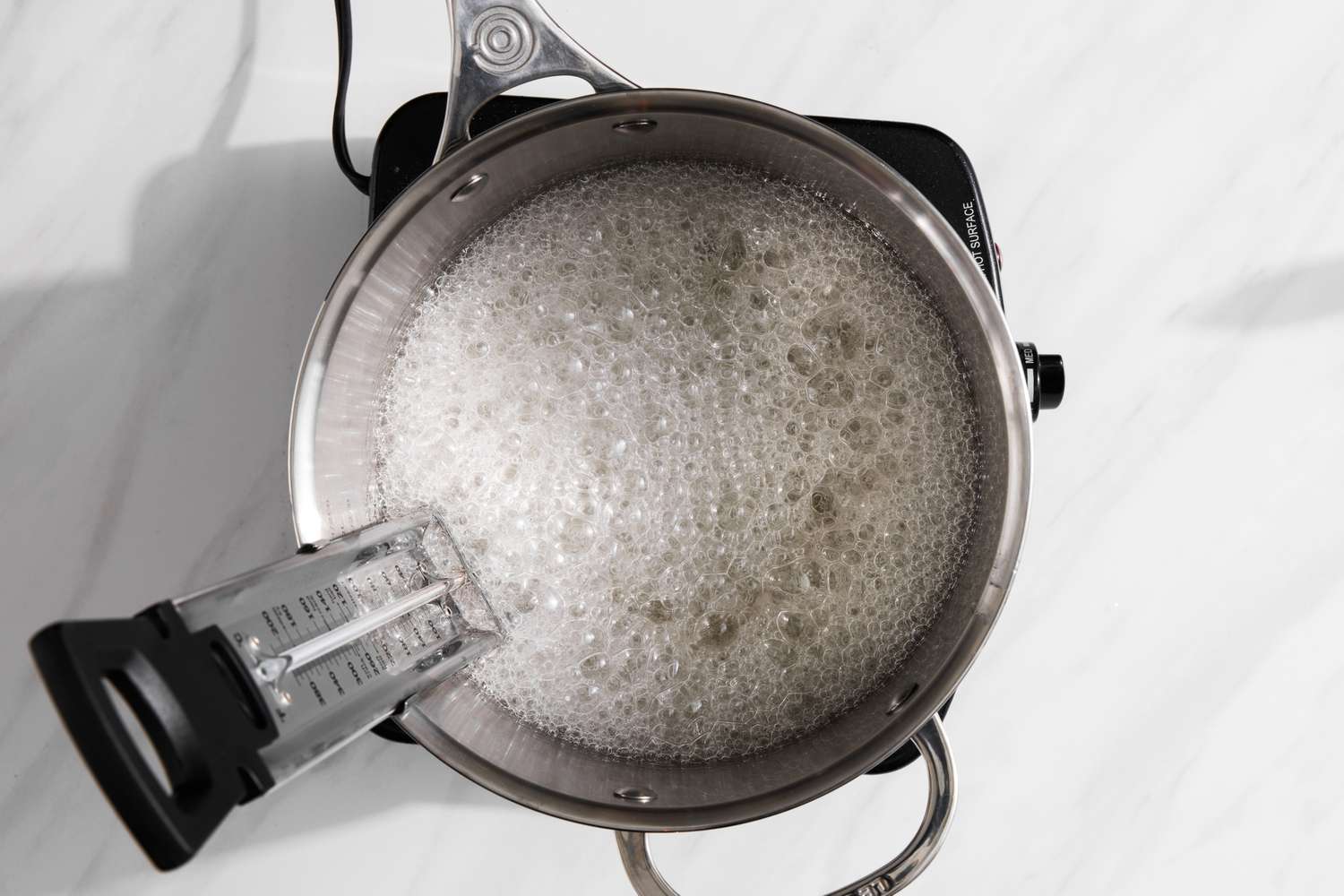 Boiling Sugar, Corn Syrup, and Water in a Sauce Pan with a Candy Thermometer in It for Holiday Caramels 