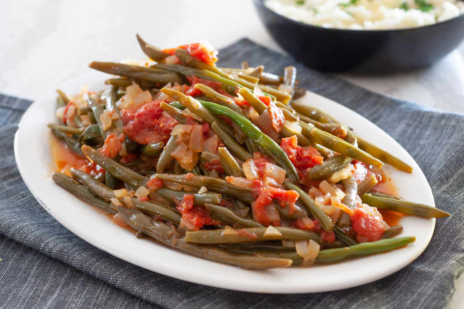 Side view of braised green beans on an oval platter.