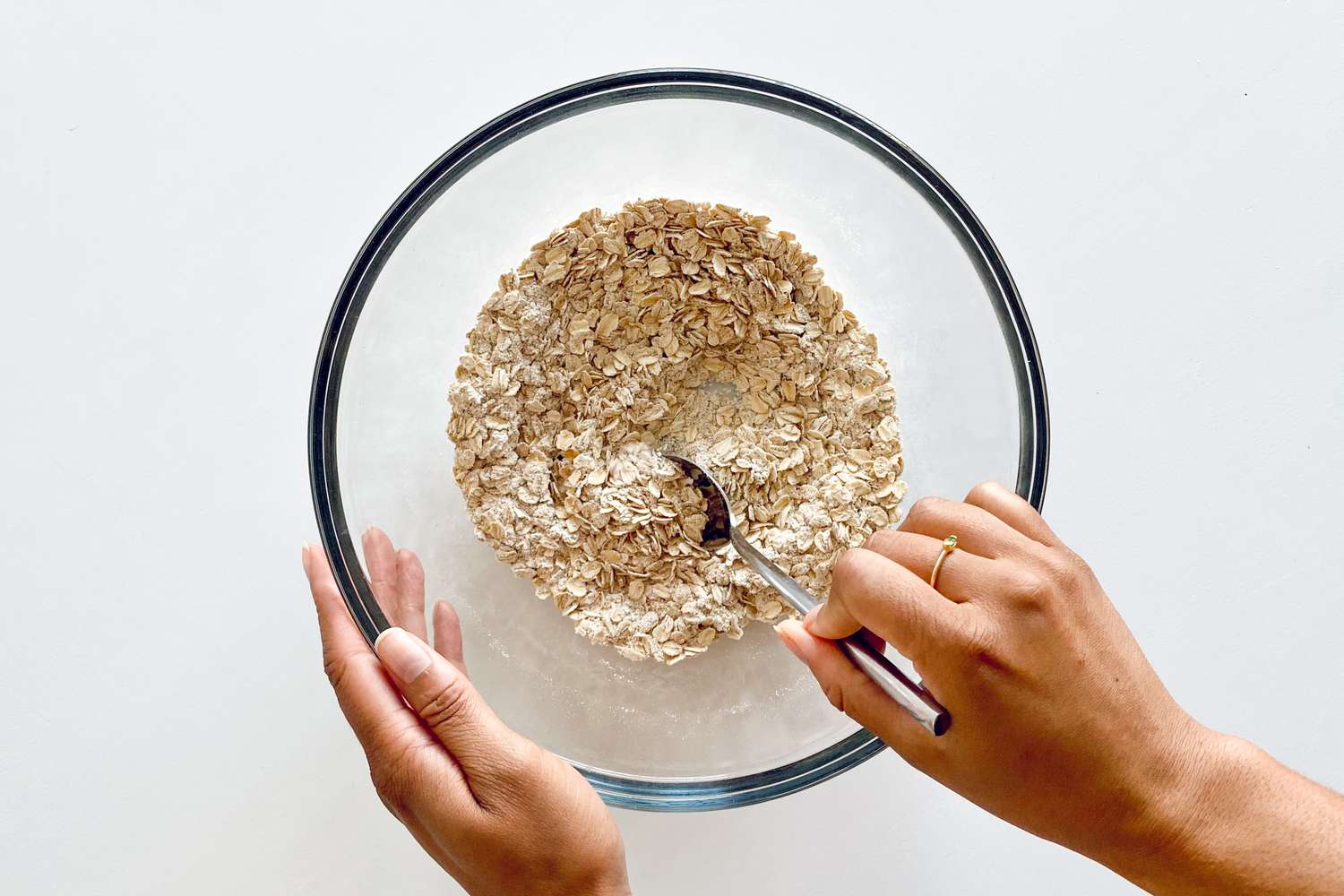 Making Chewy Fruit and Nut Granola Bars by mixing the dry ingredients in a glass bowl.
