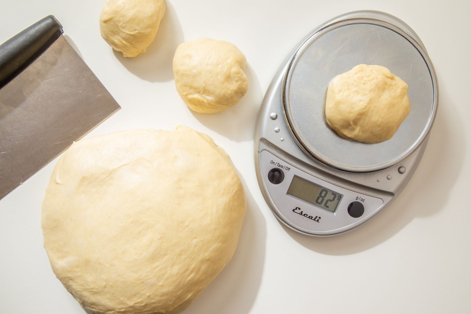 Salted honey roll dough divided into smaller doughballs and weighed on a kitchen scale (each 82 grams)
