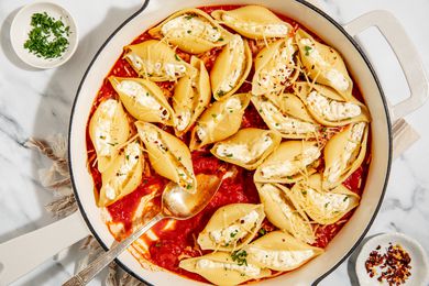Stovetop Stuffed Shells in a large pan with a large serving spoon - small dish with crushed red pepper and small dish with chopped parsley