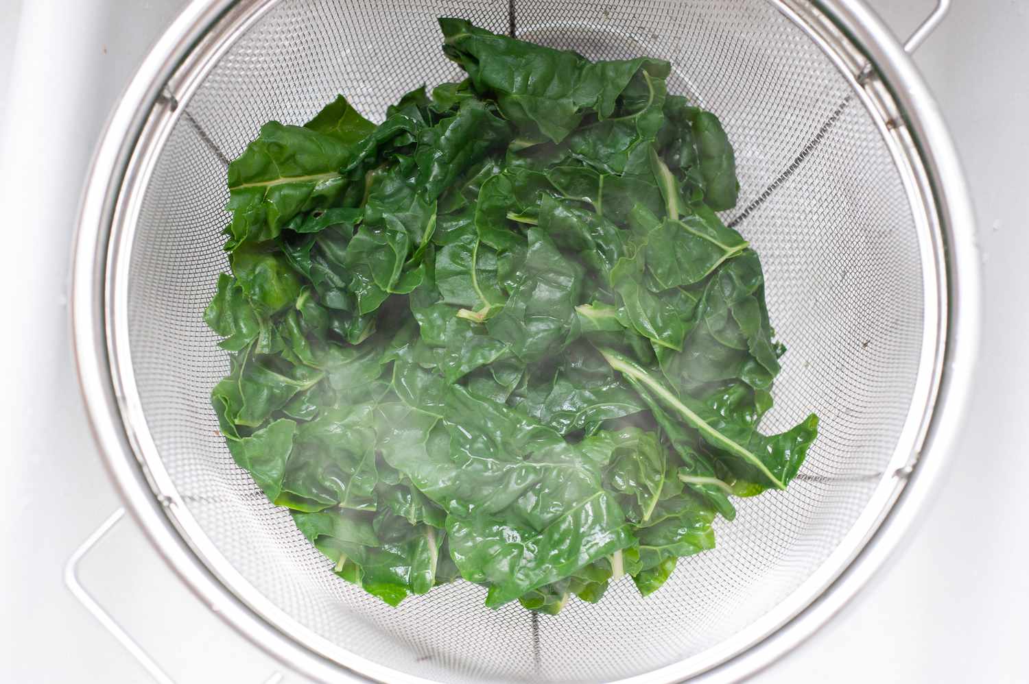 Blanched swiss chard in a colander to make a simple pasta with green sauce.