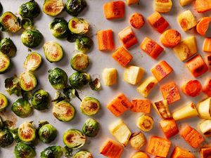 Roasted Brussels sprouts and cubes of root vegetables arranged on a sheet pan