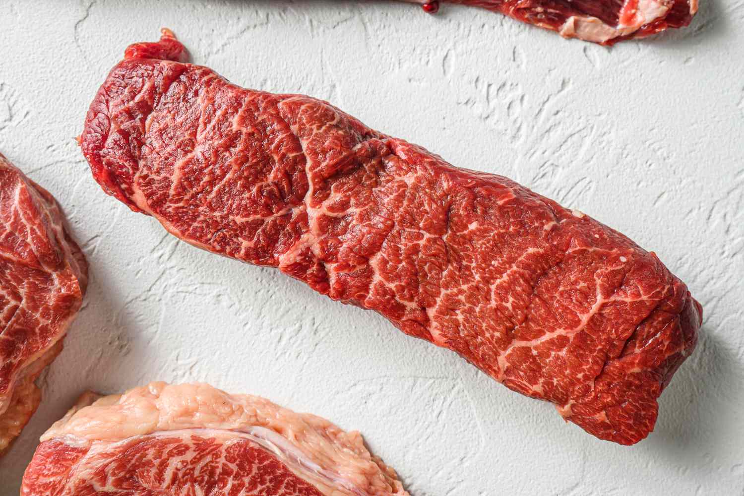 Raw cuts of beef on a light textured surface