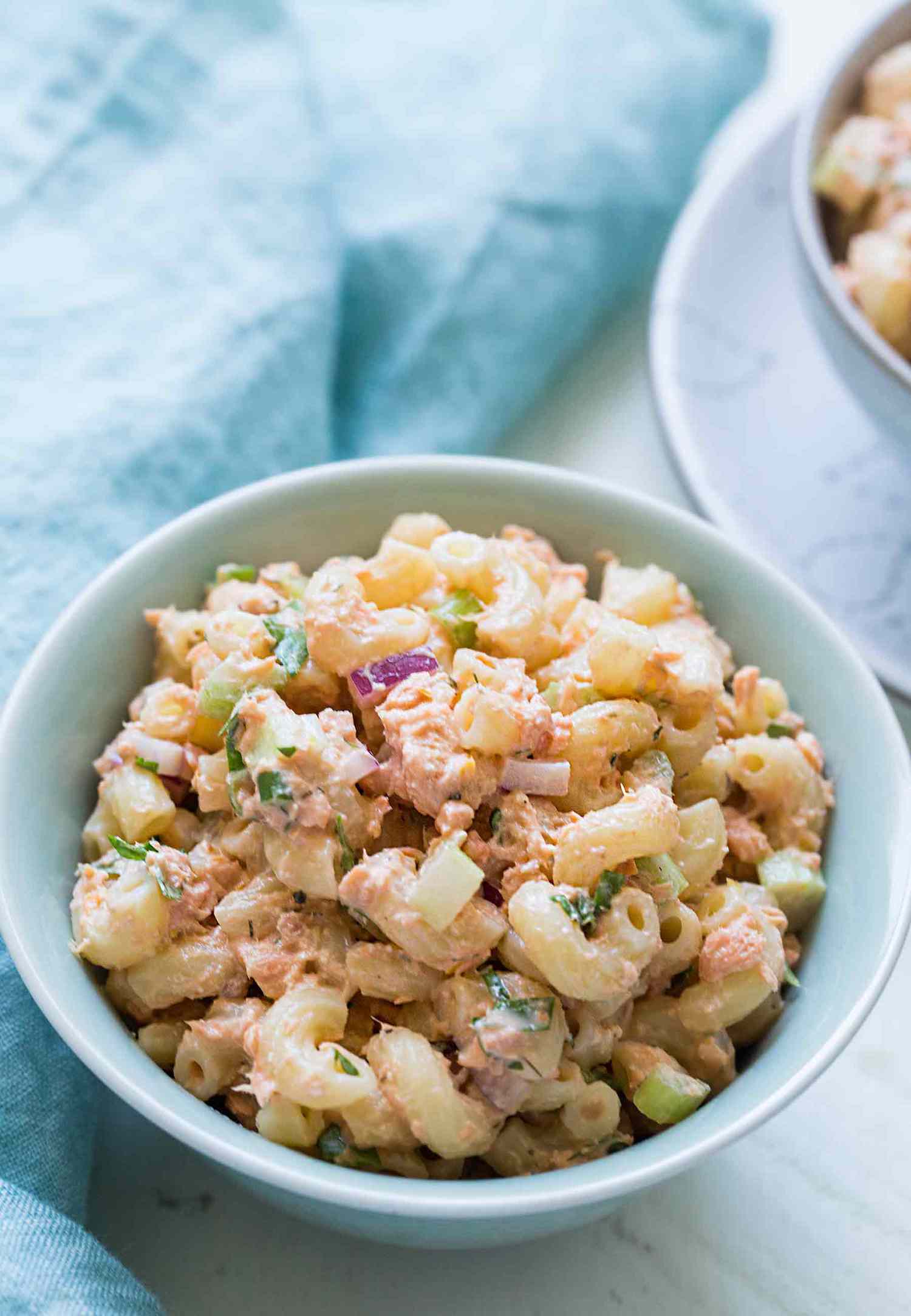 A bowl of macaroni salad with visible pieces of vegetables and seasoning