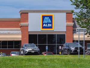 Front view of an Aldi store with cars parked in front featuring the logo prominently displayed on the building