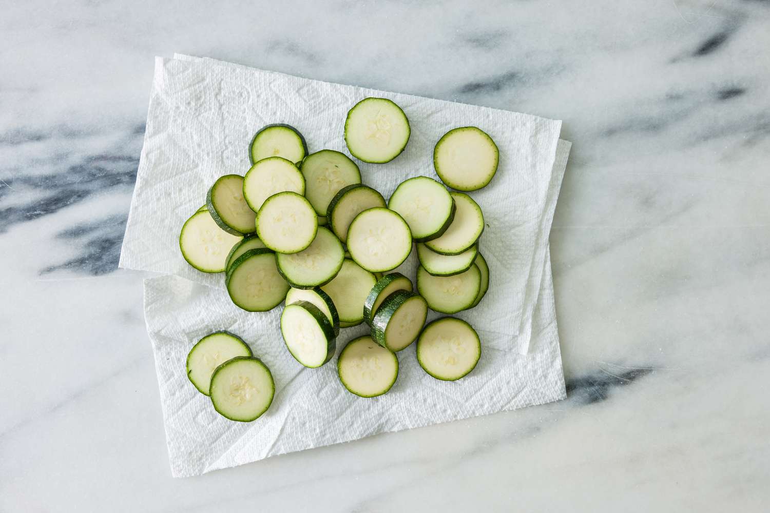 sliced and salted zucchini patted dry on paper towels for crispy chicken thighs with zucchini and shallots recipe