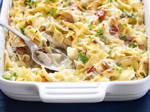 Creamy Chicken Noodle Casserole in a white baking dish with a silver spoon.