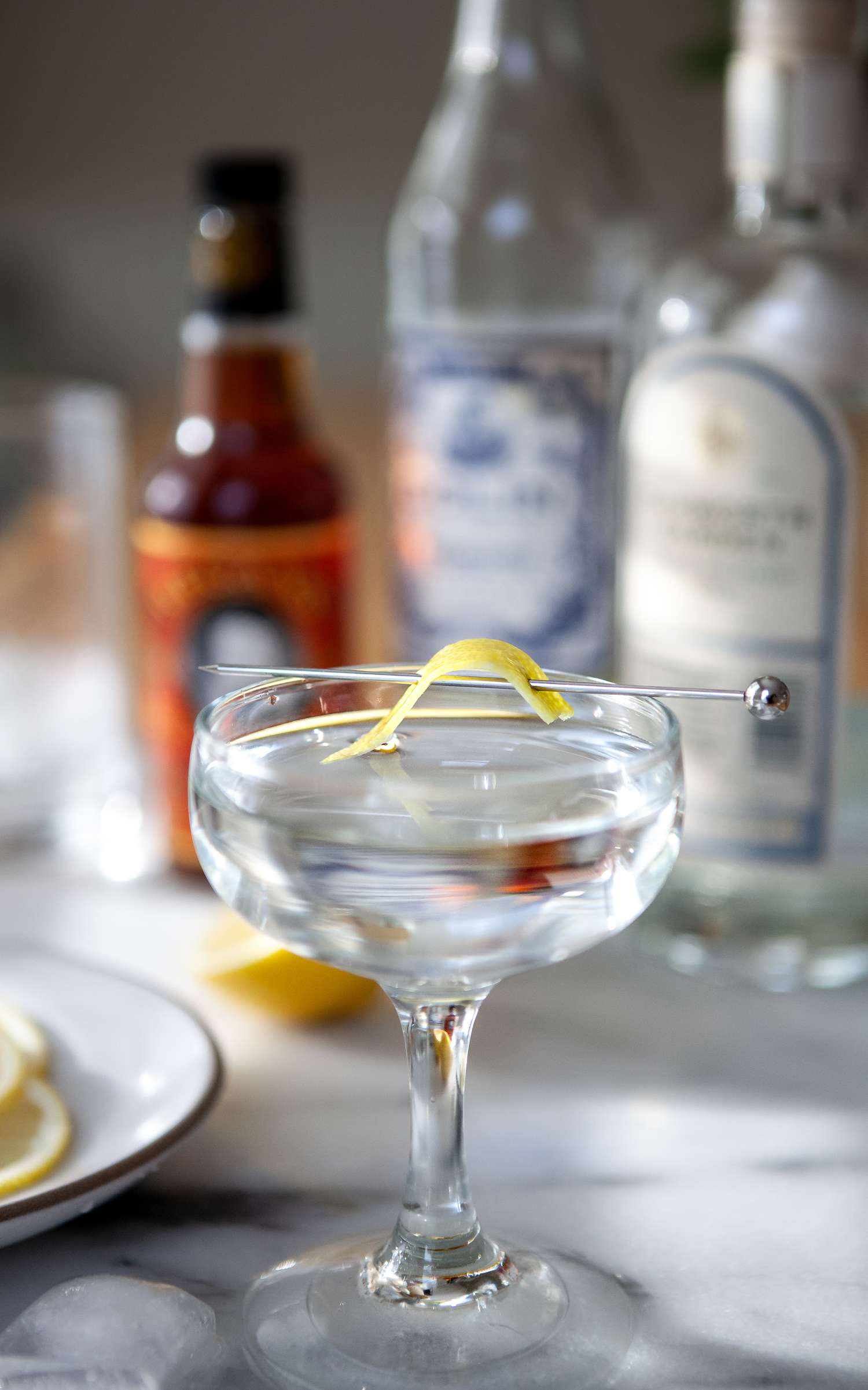 Classic Gin Martini in a coupe with bottles set behind it.