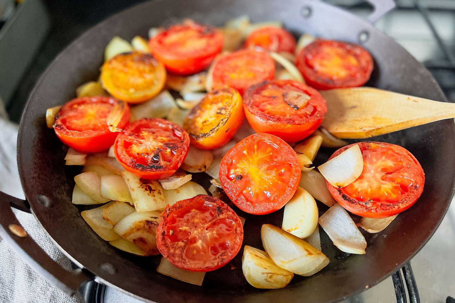 Tomatoes and onions charring in a skillet