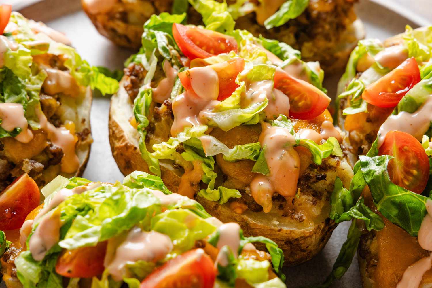 Cheeseburger stuffed baked potatoes with toppings on a plate