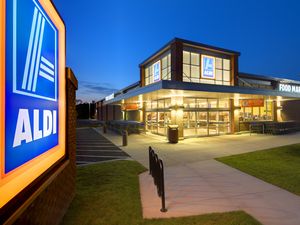 Exterior view of an Aldi grocery store at dusk with lit signage and parking area