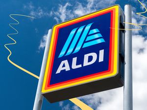 A large ALDI logo sign mounted on a pole against a blue sky background