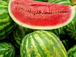 A cut piece of watermelon displayed on whole watermelons