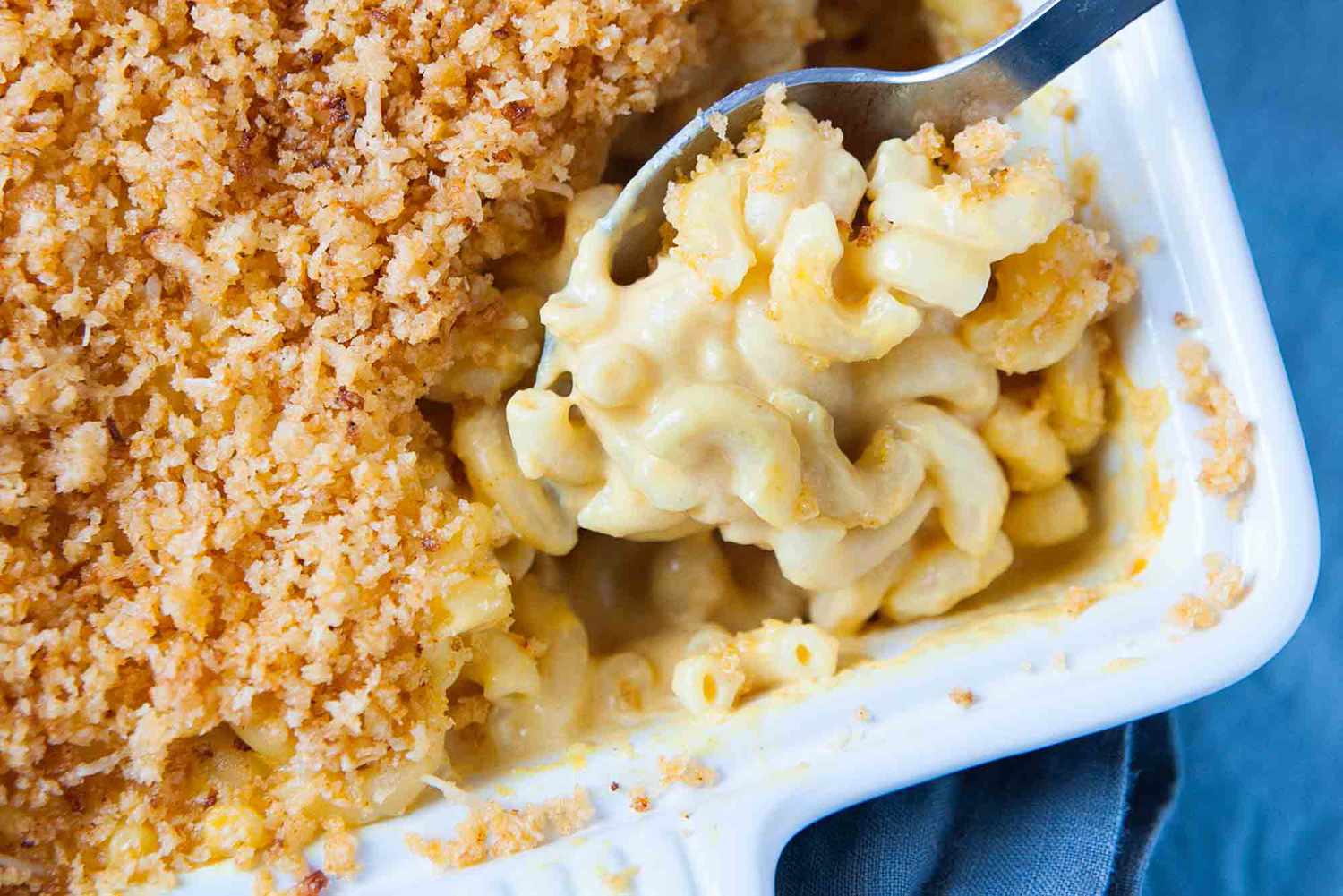 Kraft mac and cheese - a silver spoon is scooping homemade mac and cheese our of a white casserole dish