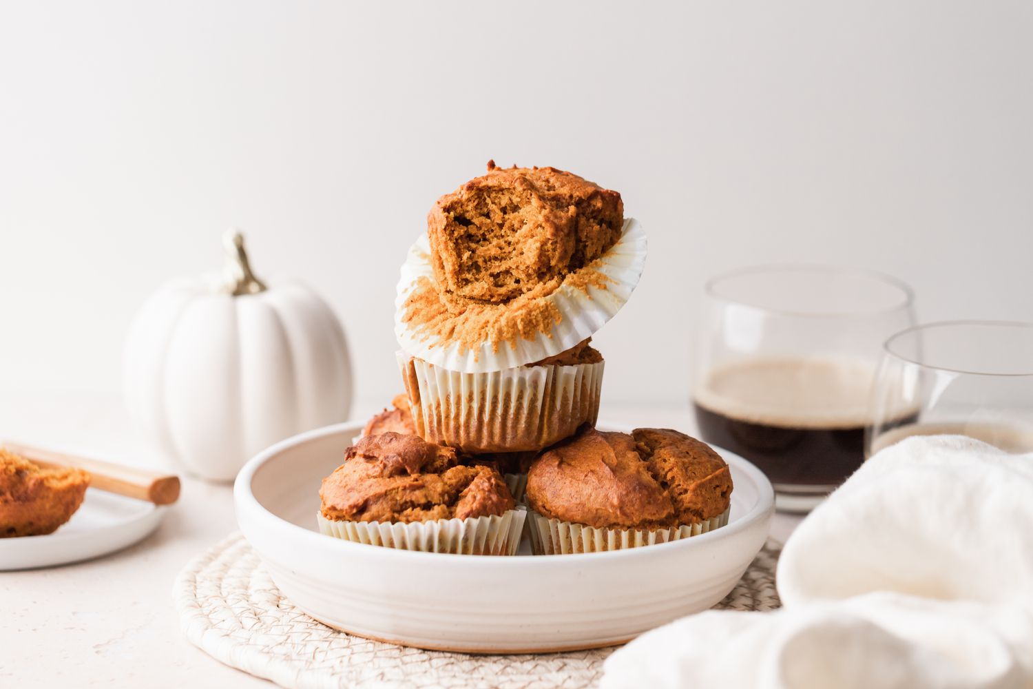 Quick and easy pumpkin muffins stacked in a serving bowl with the top one missing a bite.