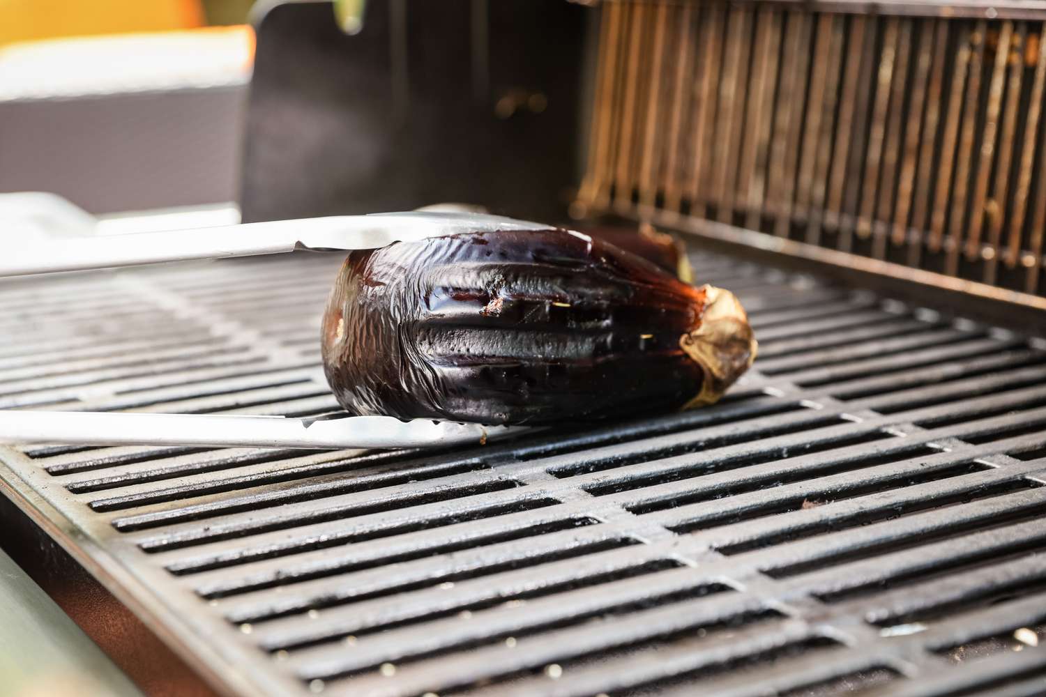 Whole Eggplant Placed on Grill with Tongs