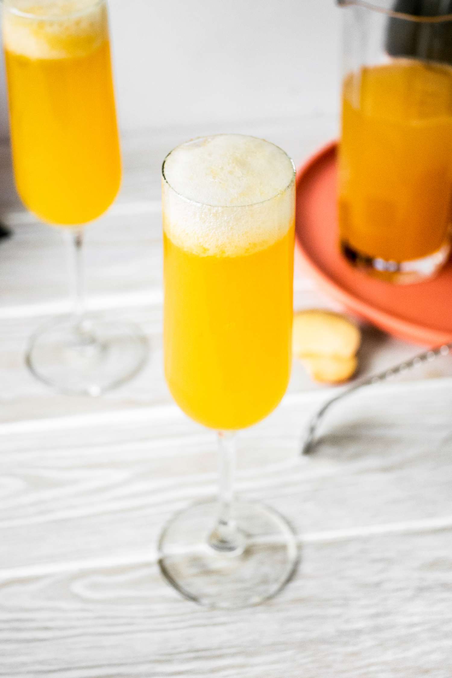 Flute of Peach Belini Cocktail Next to a Pitcher and Another Flute of Belini