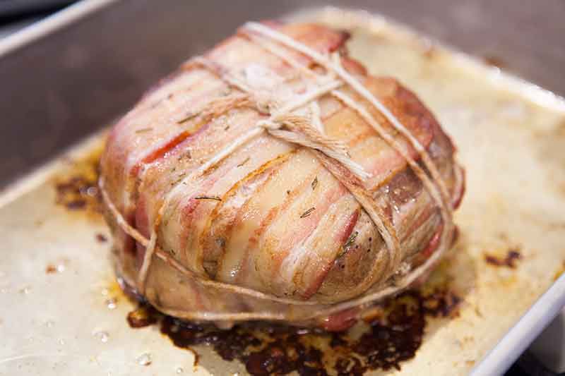 Baked bacon wrapped pork roast on pan