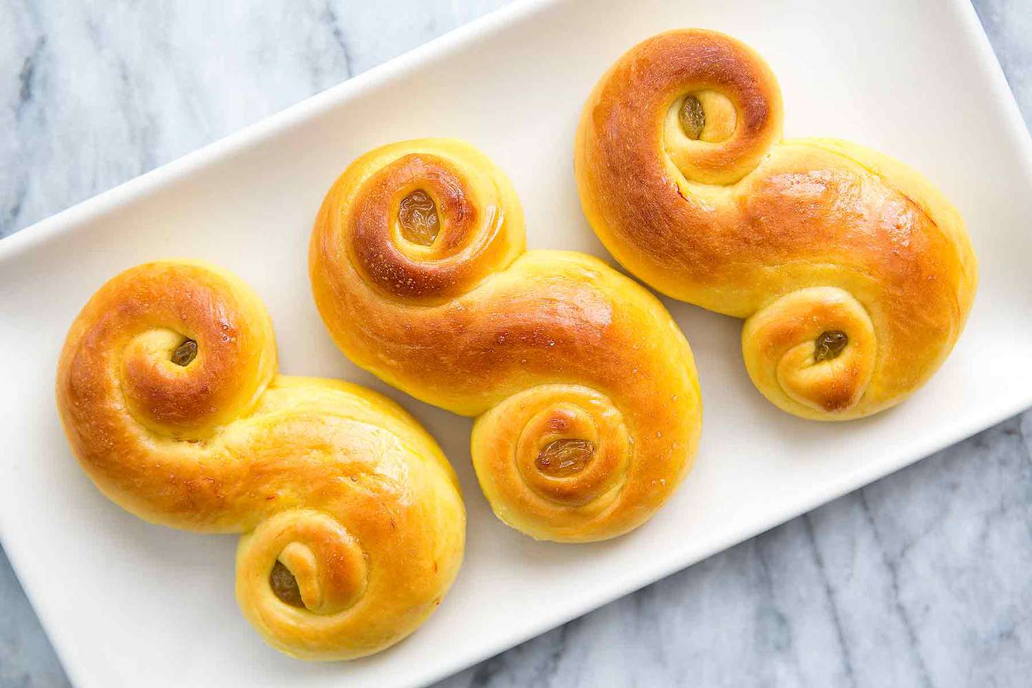 3 St. Lucia buns on a plate, ready to eat.