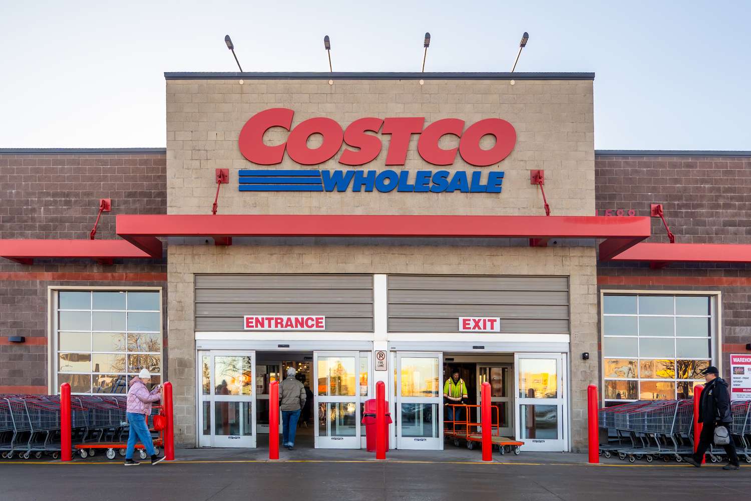 The entrance to a Costco Wholesale store with people entering and exiting marked with prominent signs
