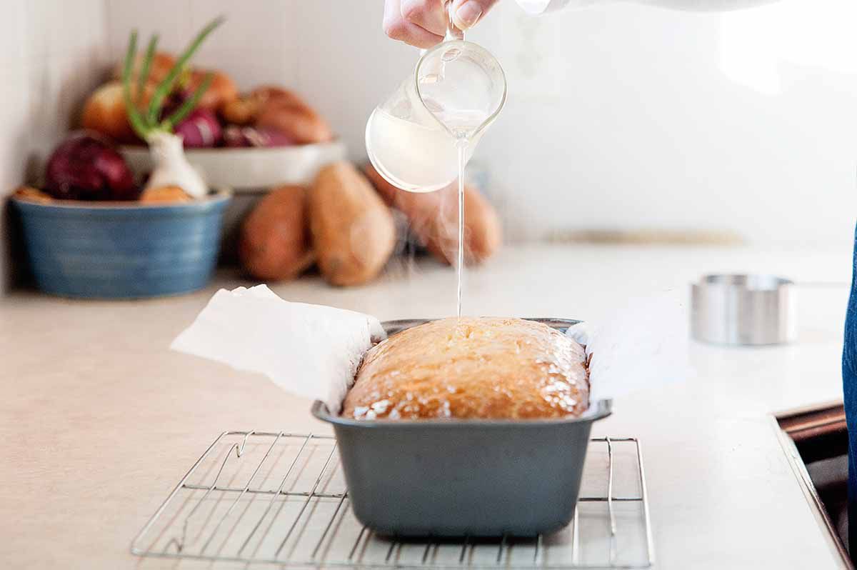 Lemon Glaze for Pound Cake - woman pouring lemon simple syrup over pound cake
