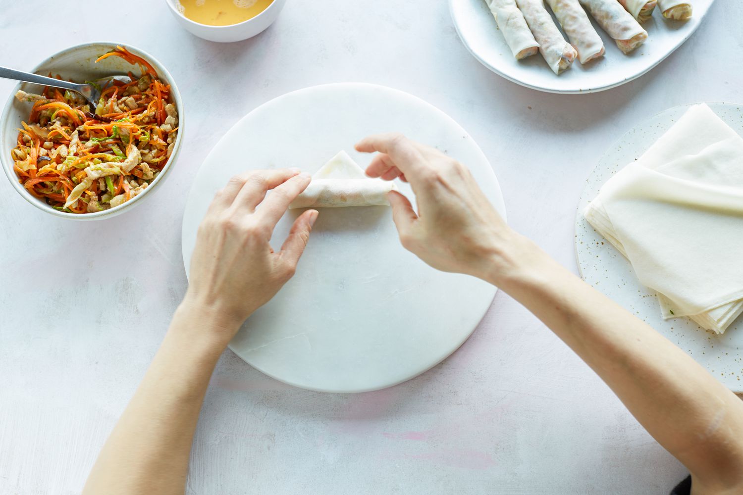 Hands showing how to roll a spring roll.