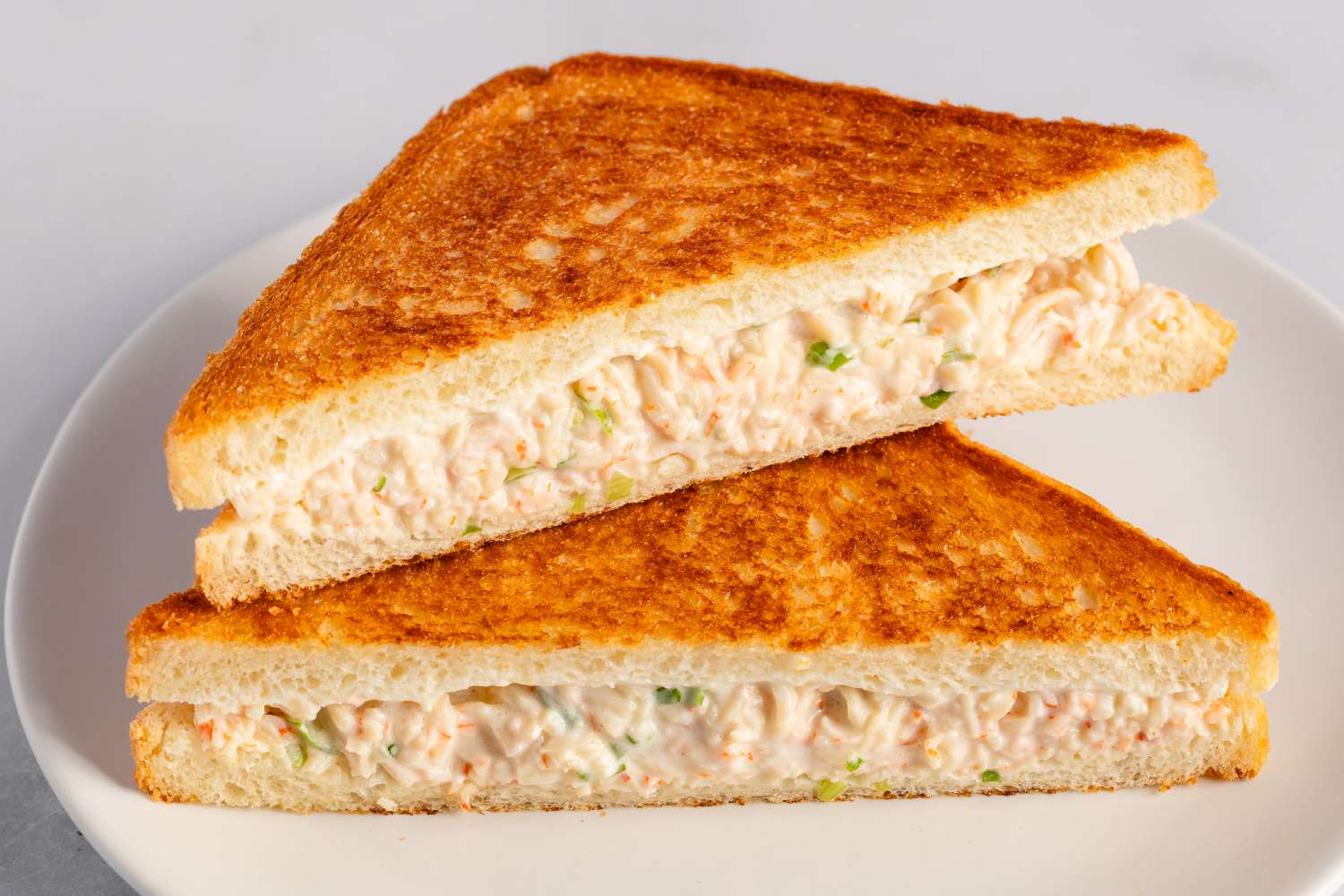 A crab rangoon sandwich cut into halves served on a plate