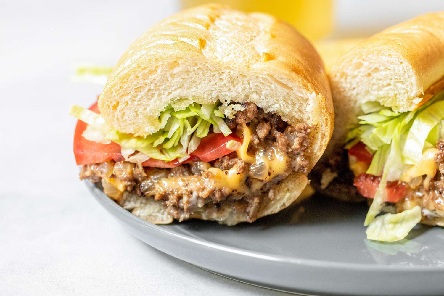 Two Halves of a Chopped Cheese Sandwich on a Plate 