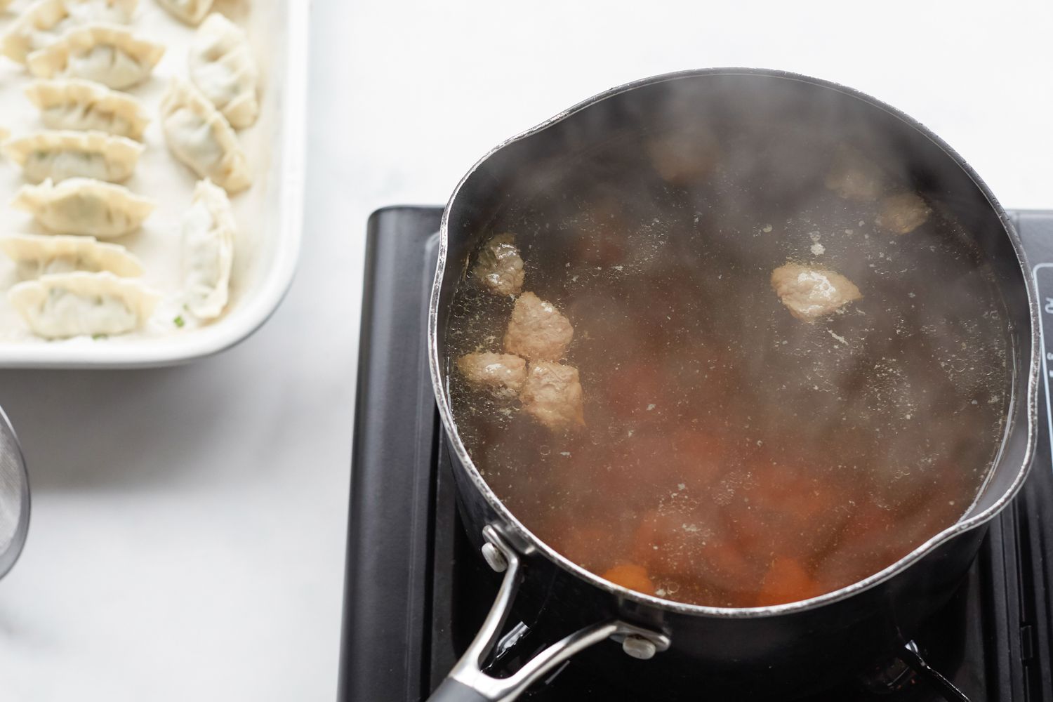 Making Korean dumpling beef soup in a pot on the stove.