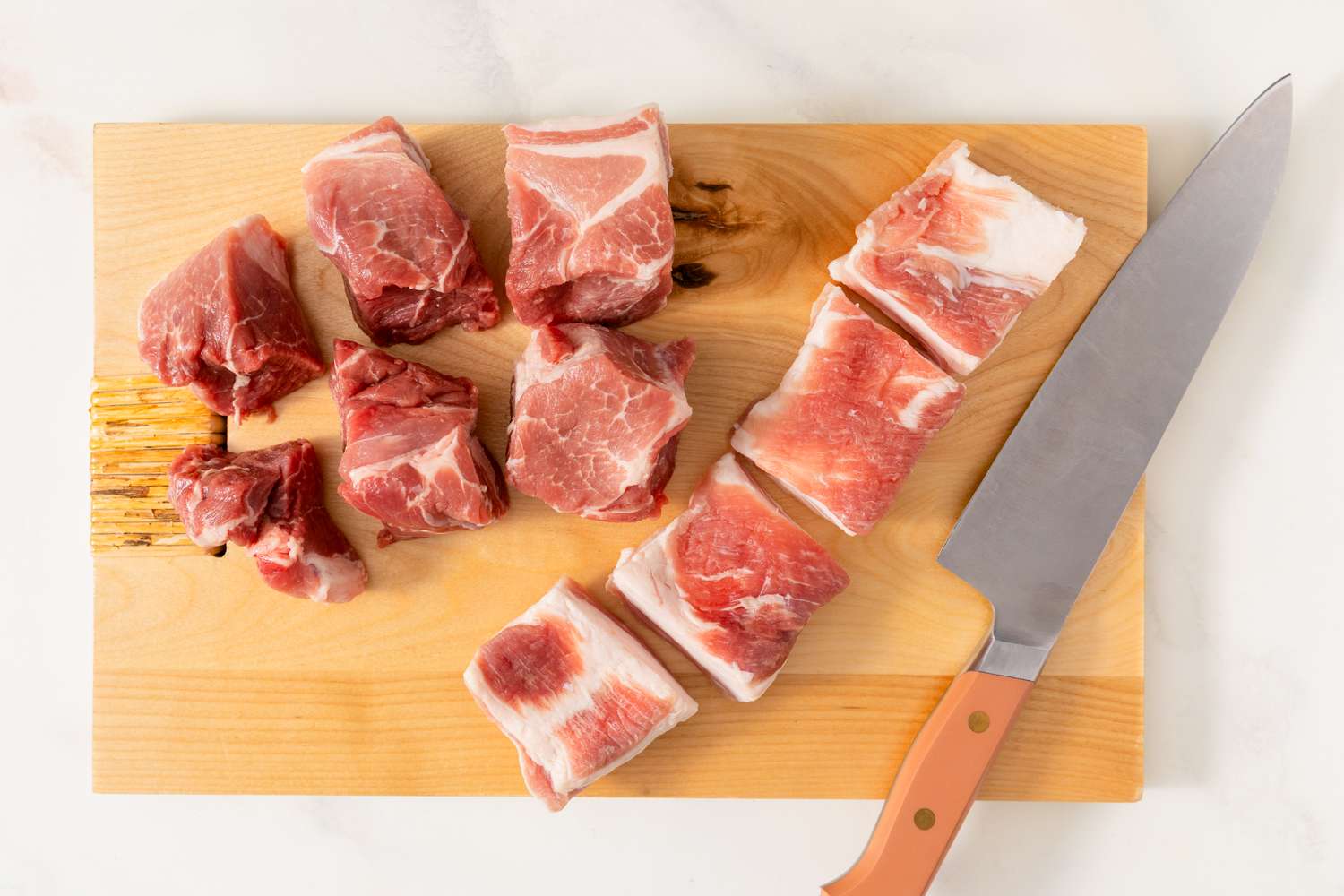 Pieces of raw pork and a knife on a cutting board