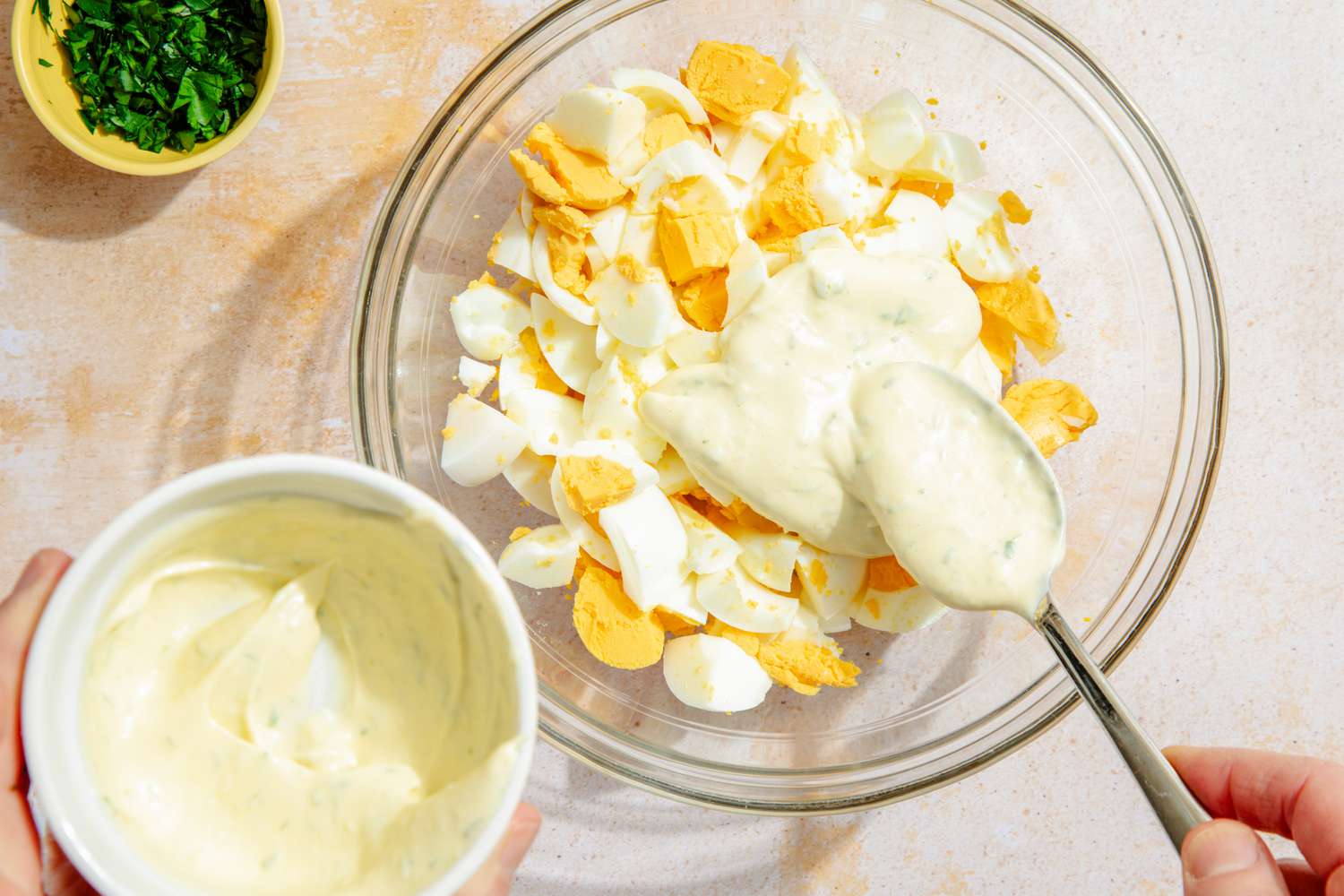 Making egg salad: Bowl of chopped eggs with dressing being spooned on top