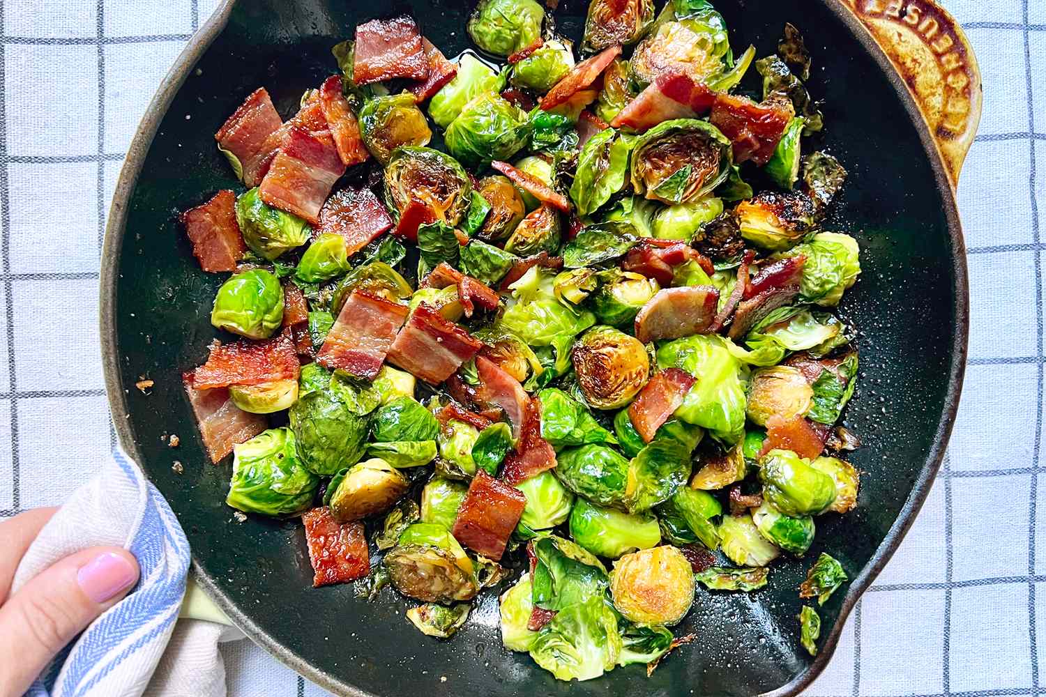 A skillet containing cooked Brussels sprouts and bacon pieces