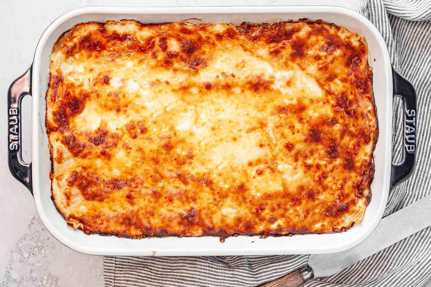 Baked Chicken Lasagna in a Casserole Dish, Resting on a Kitchen Towel 