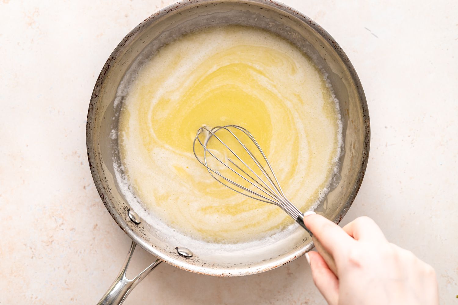 Whisking butter in a pot to show how to make browned butter.