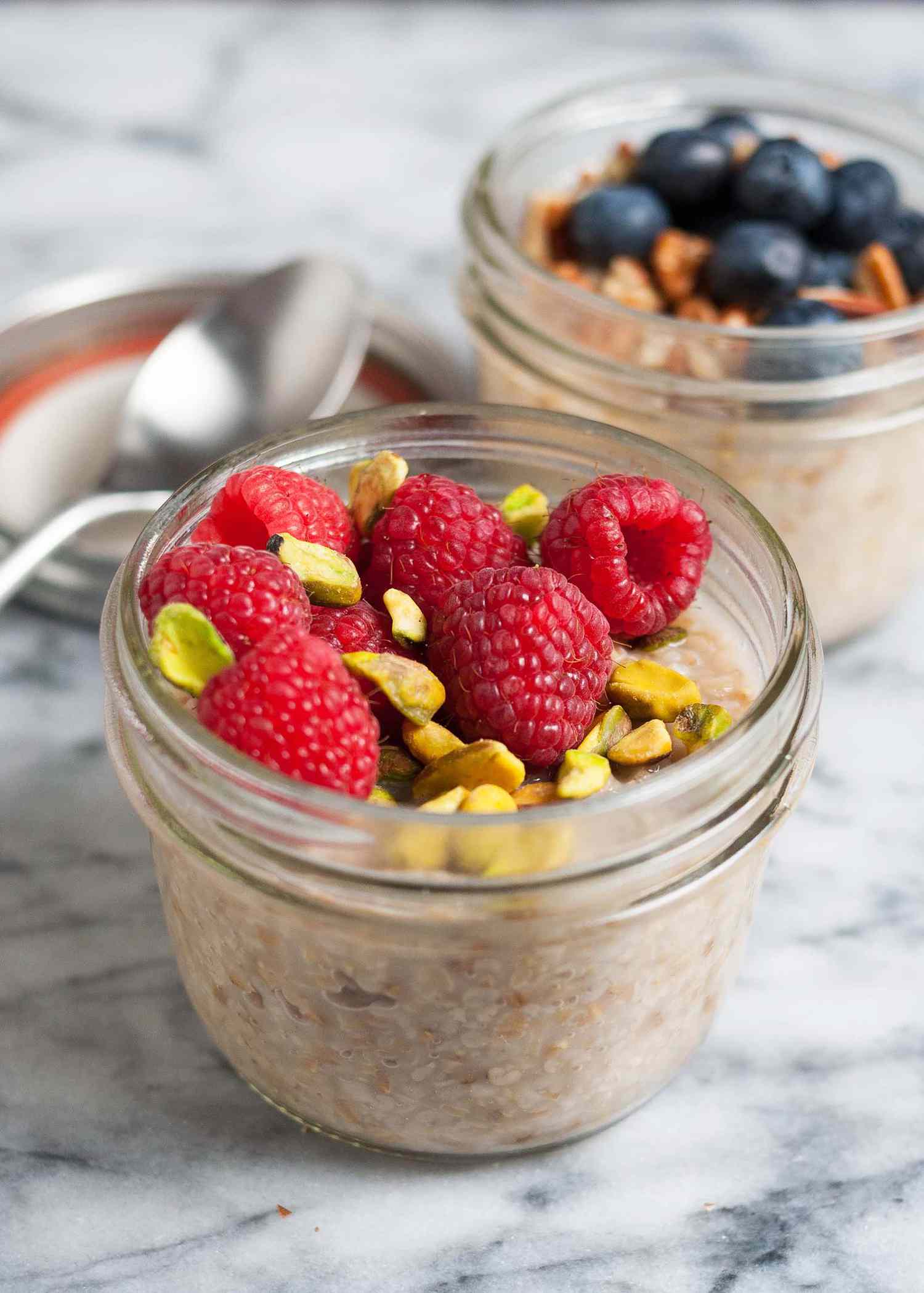 overnight steel cut oats in a jar topped with raspberries and pistachios
