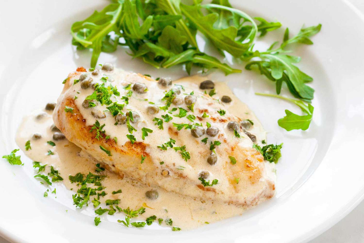 Chicken with caper mustard sauce and arugula on a plate