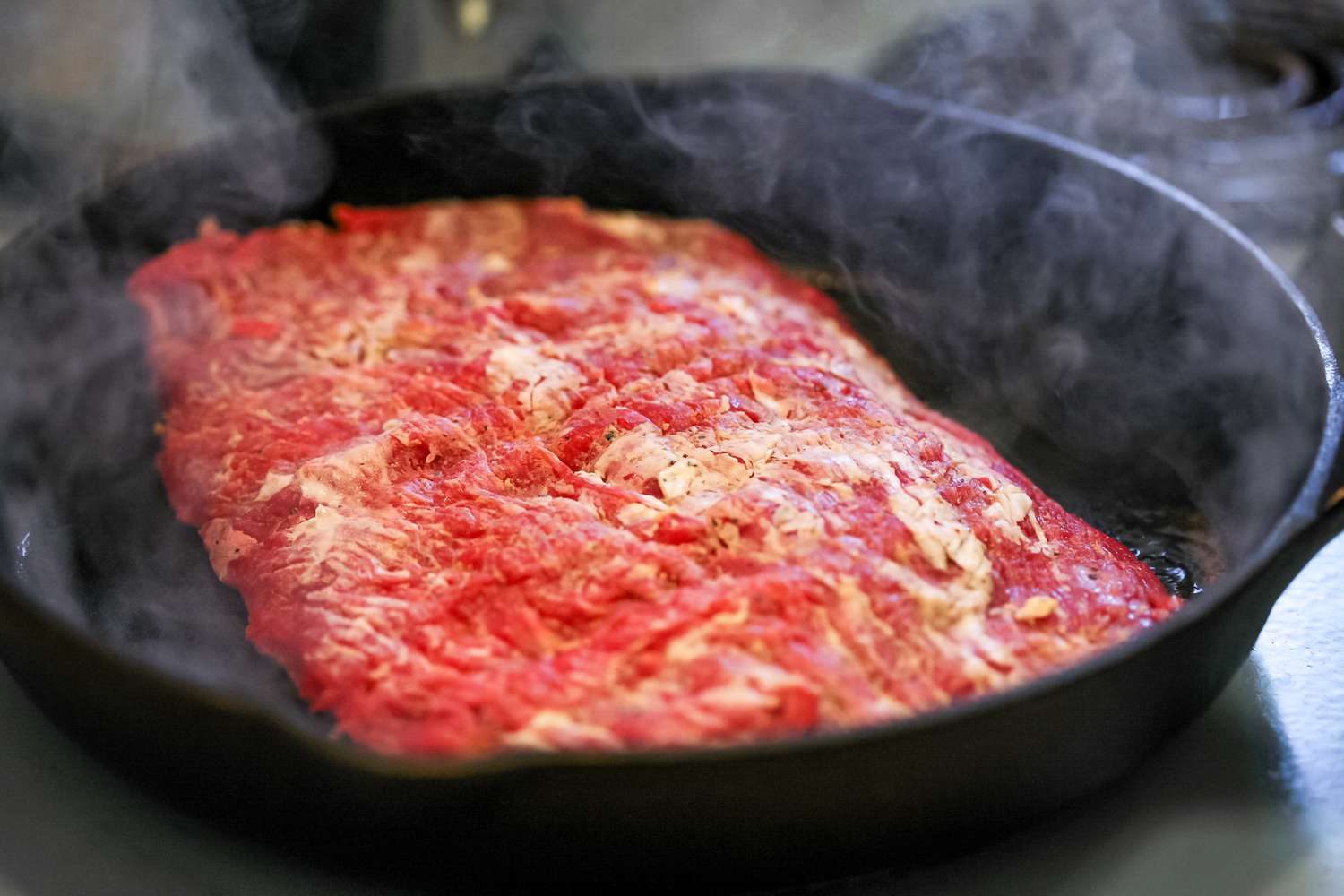 Cooking flank steak in a cast iron skillet.