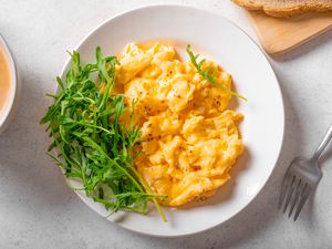 overhead view of a plate of scrambled eggs and a side of greens