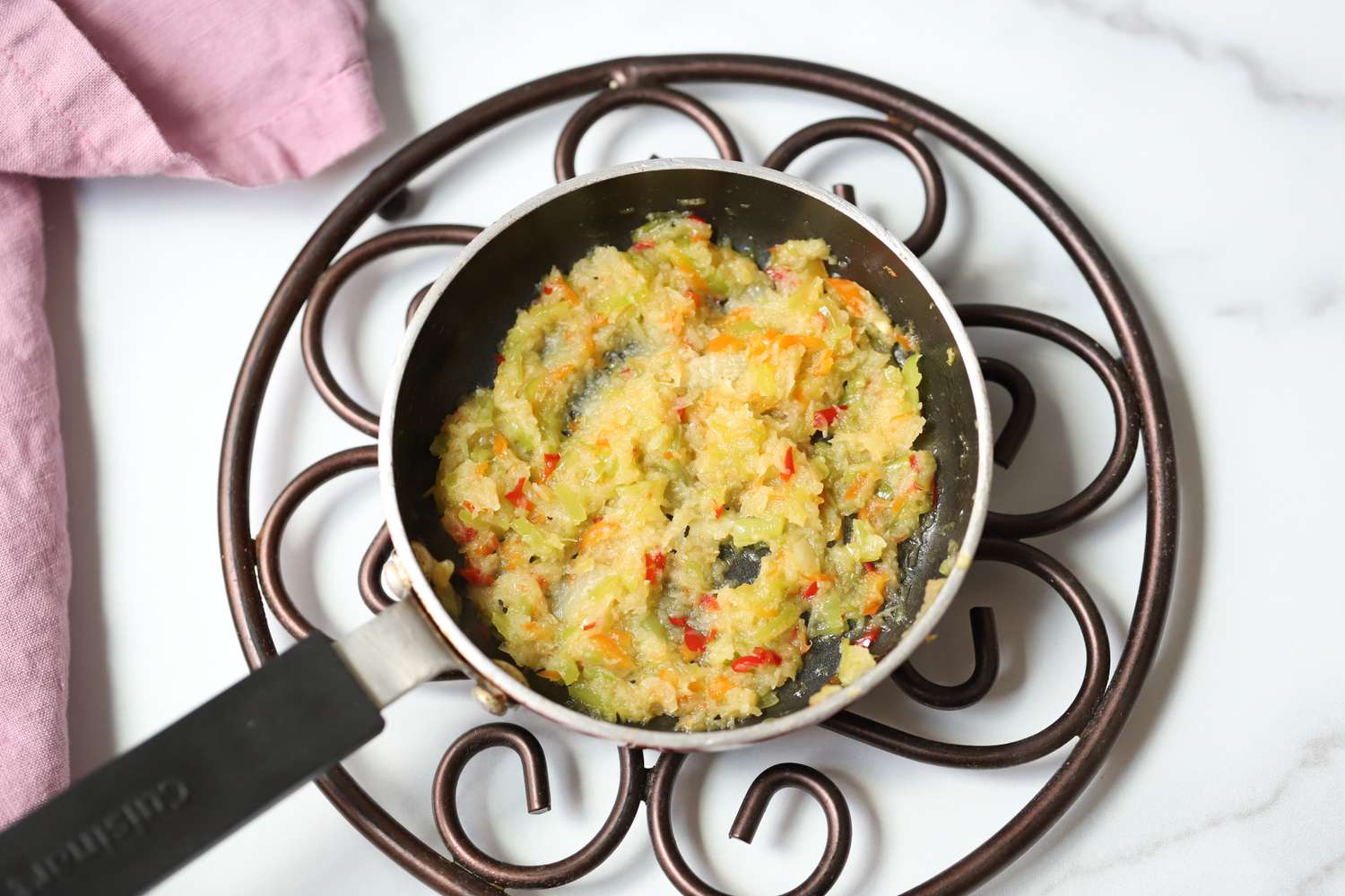 Small Skillet of Cooked Aromatics Placed on a Trivet for Trinidadian Macaroni Pie