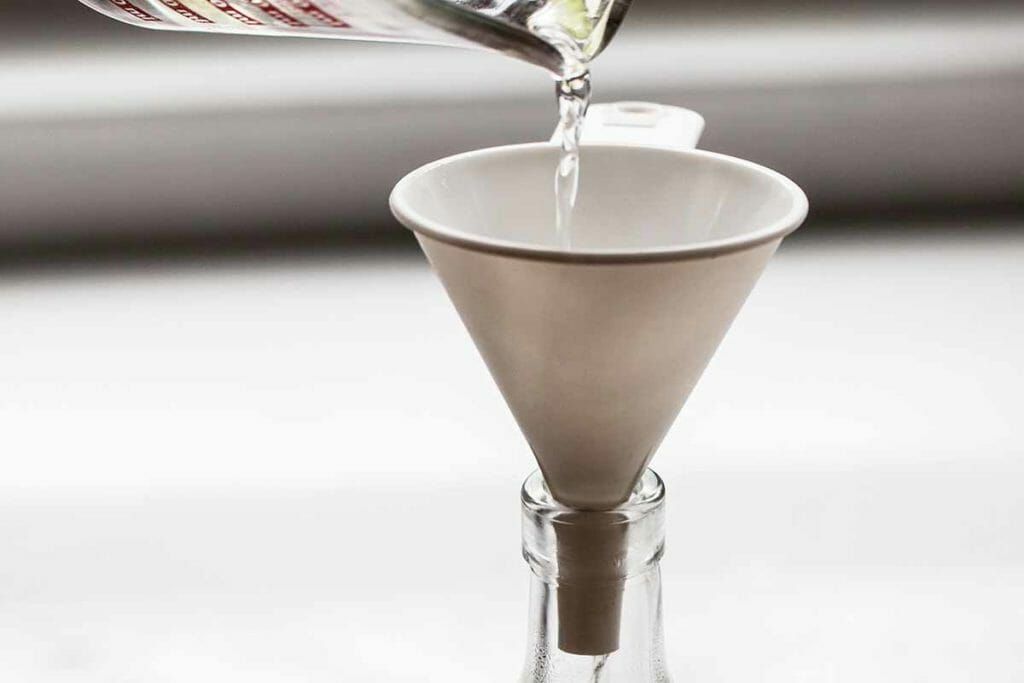 Pour simple syrup through funnel and into a bottle